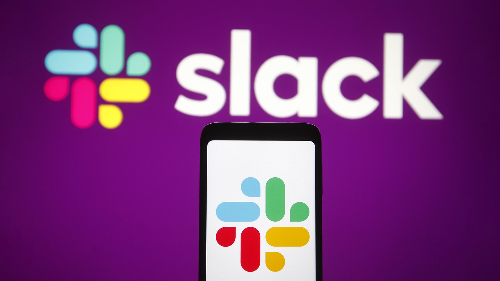 artificial intelligence The slack logo on a mobile phone in front of a purple wall with the slack logo on it