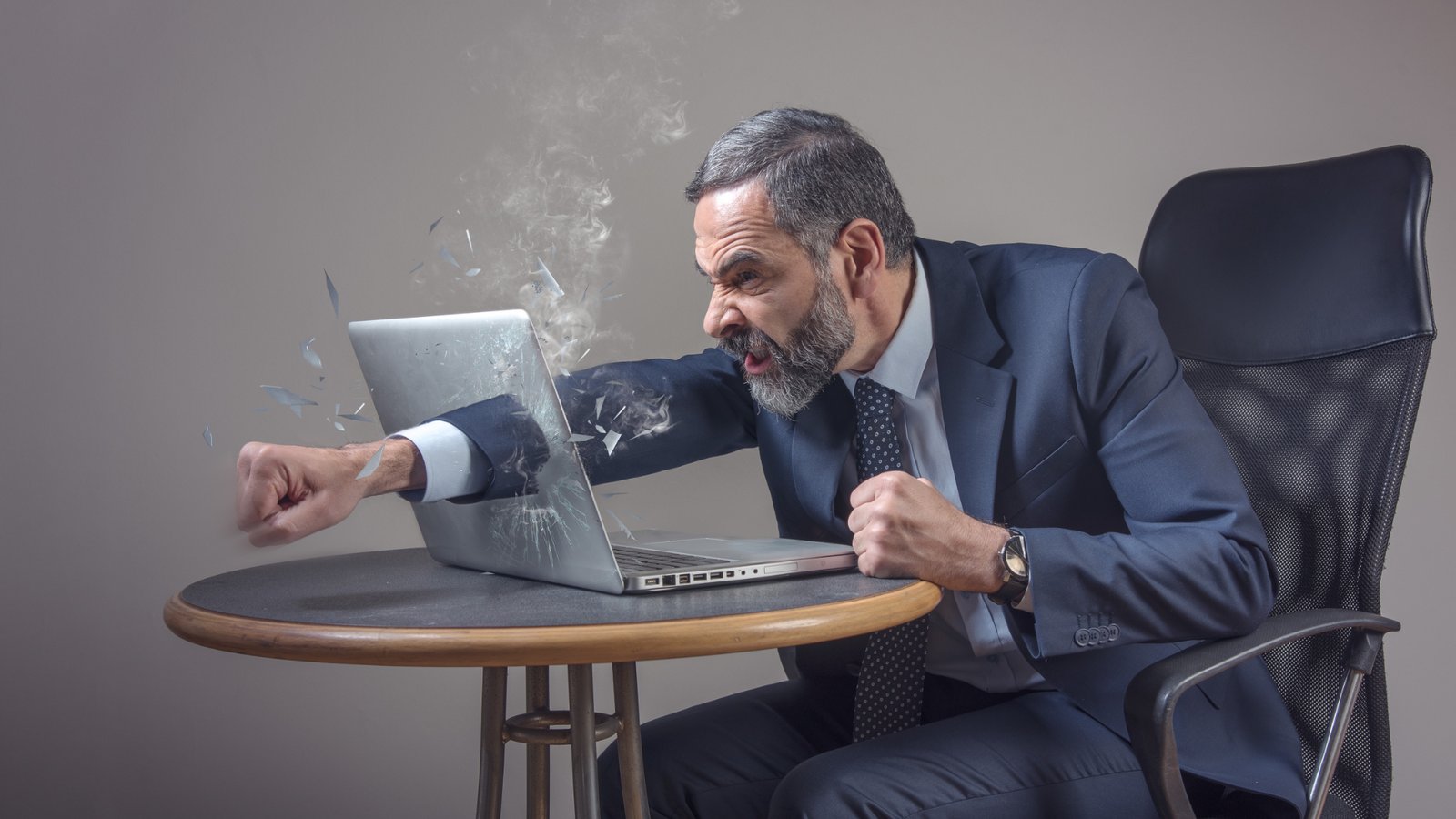machine learning Senior businessman punching a hole through his laptop screen, furious and enraged